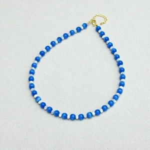 Detailed macro of glacial blue cat-eye beads and golden heart pendant clasp