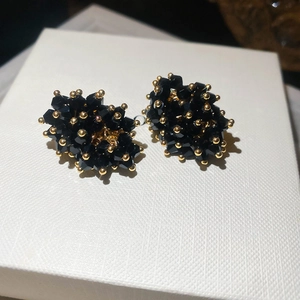 Macro shot of black crystal clustered stud earrings with gold metallic bead accents