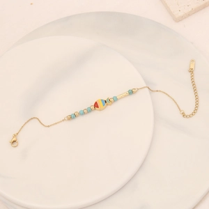 Detail of beaded fish charm bracelet with turquoise accents on marble background