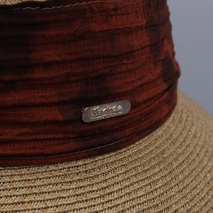 Elegant cloche straw sun hat featuring a deep brown pleated ribbon and metal logo plate