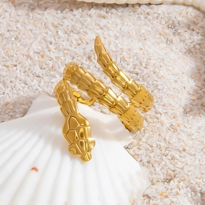 Minimalist gold snake-shaped stainless steel ring with textured detail on shell background
