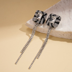 Detail of long rhinestone tassel earrings with a rectangular black enamel base and zircon