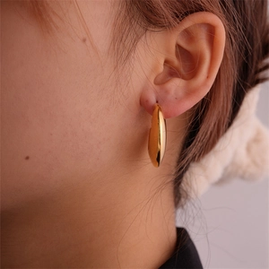 Close-up of a chunky gold hoop earring with a smooth polished finish on a model