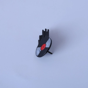 Detail of melting vinyl record enamel pin with black liquid effect and red center