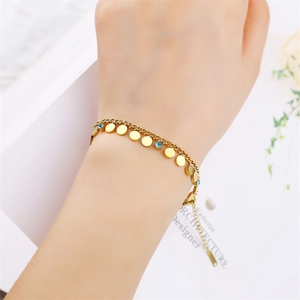Detailed view of a gold double-layer chain bracelet with blue zircons on a wrist