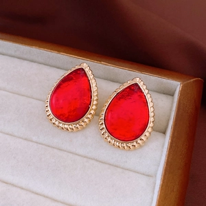 Macro shot of vintage red teardrop earrings with golden twisted metal texture frames