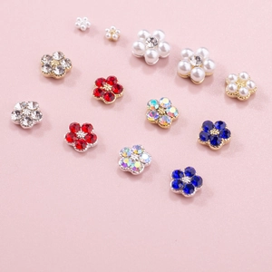 Detailed macro view of mixed crystal five-petal flower nail charms with pearls and rhinestones