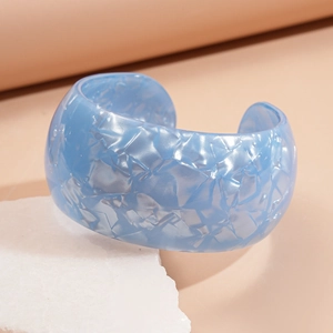 Macro shot of light blue acrylic open bangle with natural marble texture on stone
