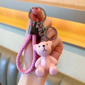 Close-up of pink resin bear keychain with woven leather strap and lobster clasp detail