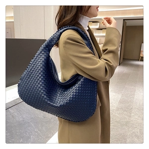 Detail showing deep blue woven leather texture and integrated strap of the hobo bag