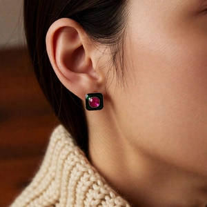 Close-up of vintage square earrings with dark green enamel and red crystal inlay