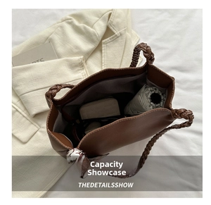 Macro view of a large brown tote bag showing capacity with a wallet and umbrella inside