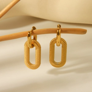 Golden textured oval link drop earrings in stainless steel on a rustic wooden branch