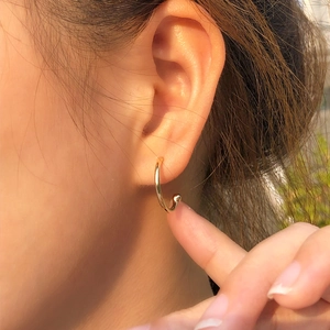 Close-up of elegant gold hoop earrings with small bead detail on female model