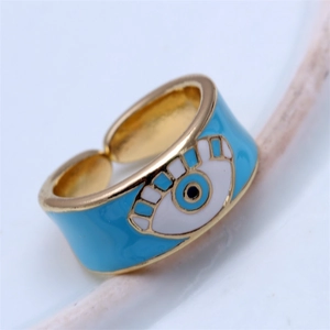 Close-up of adjustable gold ring with light blue enamel evil eye charm on white background