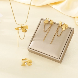 Detail of gold bow jewelry set with pearls and tassels on warm silk fabric