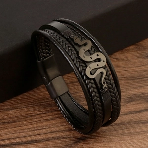 Detail of multi-layer black braided leather bracelet with snake-shaped metal charm and magnetic clasp
