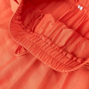 Vue détaillée de la taille élastique froncée sur un pantalon orange avec étiquette S