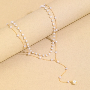 Detail of elegant gold double-layer necklace featuring white pearls and a long tassel drop