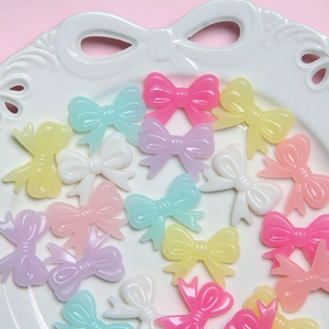 Colorful resin bow beads for DIY phone chains and bracelets on a white decorative plate