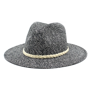 Détail de la texture tressée d'un chapeau de paille à bord large avec ruban beige