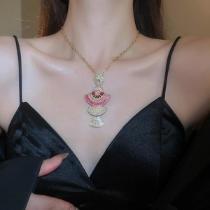 Detailed view of golden necklace with three-tier fan pendant and rubies on model