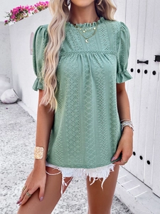Detail of green eyelet embroidered top with ruffle collar and puff sleeves on model