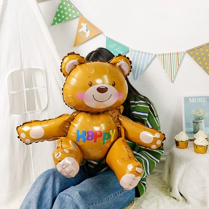 Detail of large brown teddy bear foil balloon with Happy text in a party setting