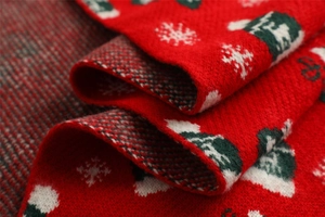 Close-up of red Christmas knit scarf featuring white snowflakes and green tree patterns
