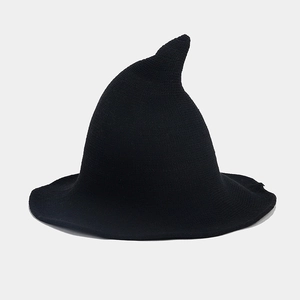 Detailed close-up of a black knitted wizard hat with pointed tip and wide flat brim