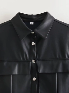 Close-up of the collar and dual pockets on a black PU leather shirt jacket with size S label