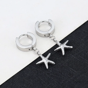 Macro shot of silver starfish charm earring with polished finish on a modern backdrop