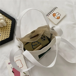Minimalist white canvas bucket bag shown from above with phone and daily essentials
