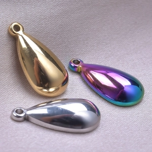 Macro shot of three teardrop pendants in gold, silver and rainbow finishes on fabric