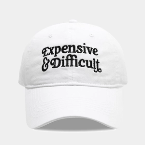 Close-up of black 'Expensive & Difficult' embroidery on a white cotton baseball cap