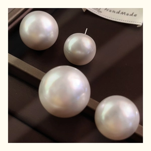 Macro shot of oversized white pearls with iridescent luster on a brown handmade display tray