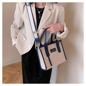 Detail view of canvas tote bag with blue leather trim and wide woven shoulder strap