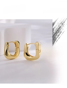 Macro shot of minimalist gold-plated U-shaped earrings with high-polished glossy surface