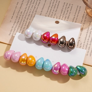 Colorful teardrop acrylic earrings set on display card with vintage newspaper backdrop