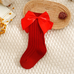 Gros plan de chaussettes de Noël pour bébé avec rayures verticales et gros nœud en satin