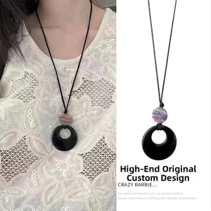 Detailed view of ethnic style black resin ring pendant necklace on lace background