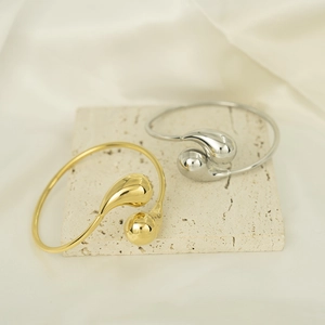 Minimalist 18K gold and silver chunky teardrop bangles on a stone display board