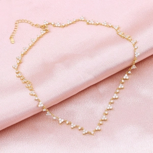 Detailed macro view of a gold chain necklace with sparkling triangular zircon clusters