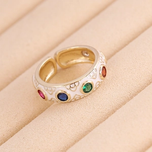 Macro shot of white enamel gold ring with colorful gemstones on a beige display