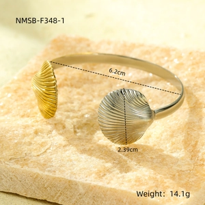 Detail of open bangle featuring dual-tone scallop shell motifs and product dimensions