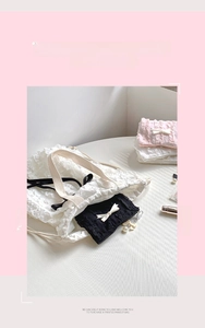 Dettaglio set pochette trucco in pizzo increspato con eleganti fiocchi bianchi e perle