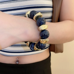 Close-up of deep blue round beads and irregular golden spacers on a stylish wrist bracelet