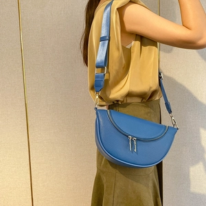 Blue lychee leather half moon crossbody bag with wide shoulder strap on model