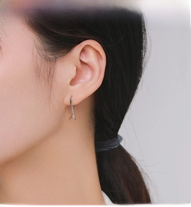 Close-up of minimalist S925 sterling silver geometric cross earrings worn by a model