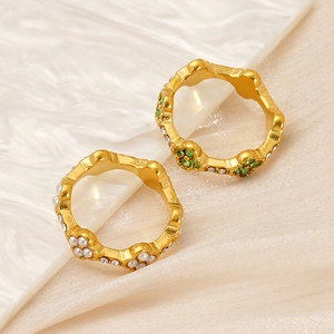 Detailed macro of 18K gold flower rings with green zircons and white pearls